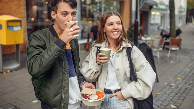 två unga personer dricker ur pappersmuggar